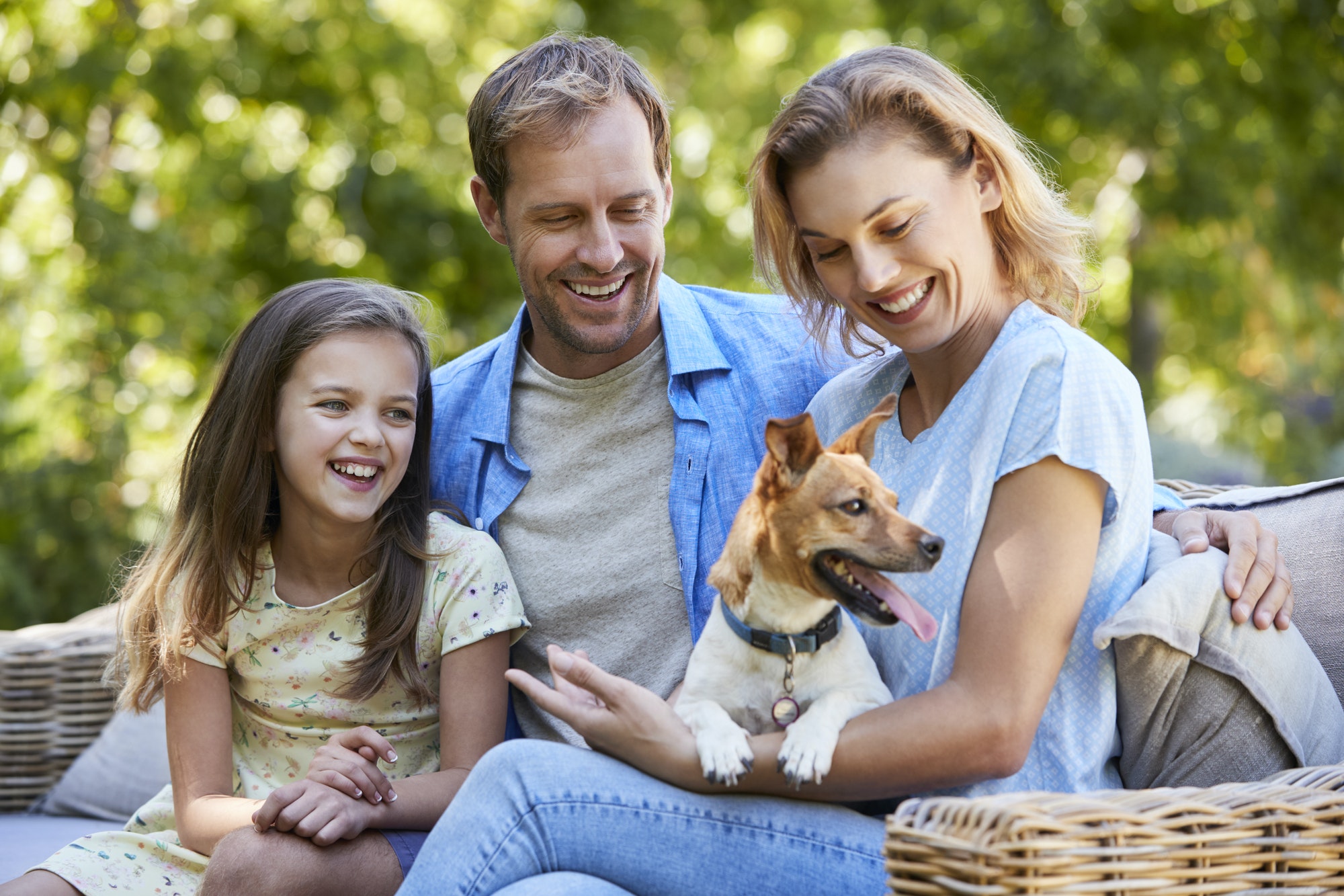 Parents and daughter sitting with their dog in the garden