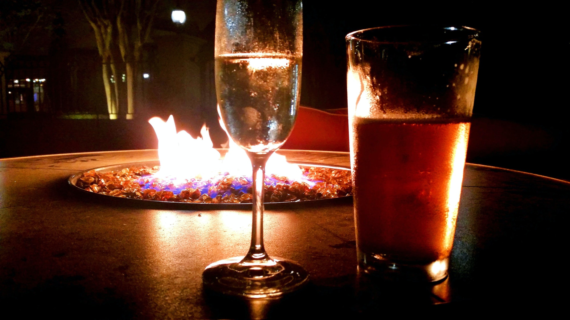Enjoying a glass of wine and pint of beer next to a fire pit on date night. Enjoying a glass of wine and pint of beer next to a fire pit on date night.