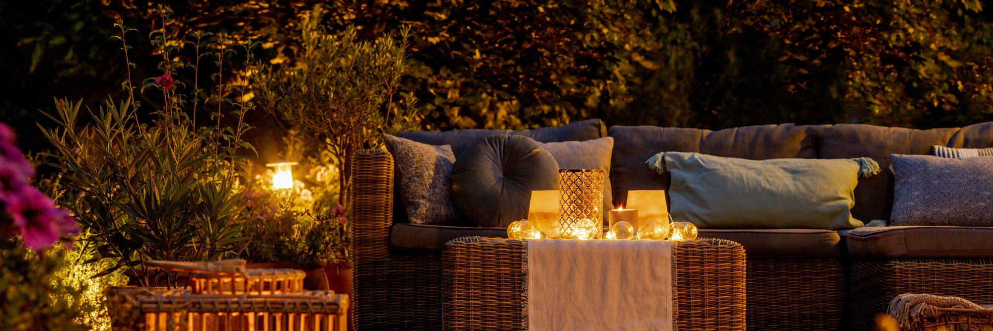 Trendy furniture, lights, lanterns and candles in the garden at night