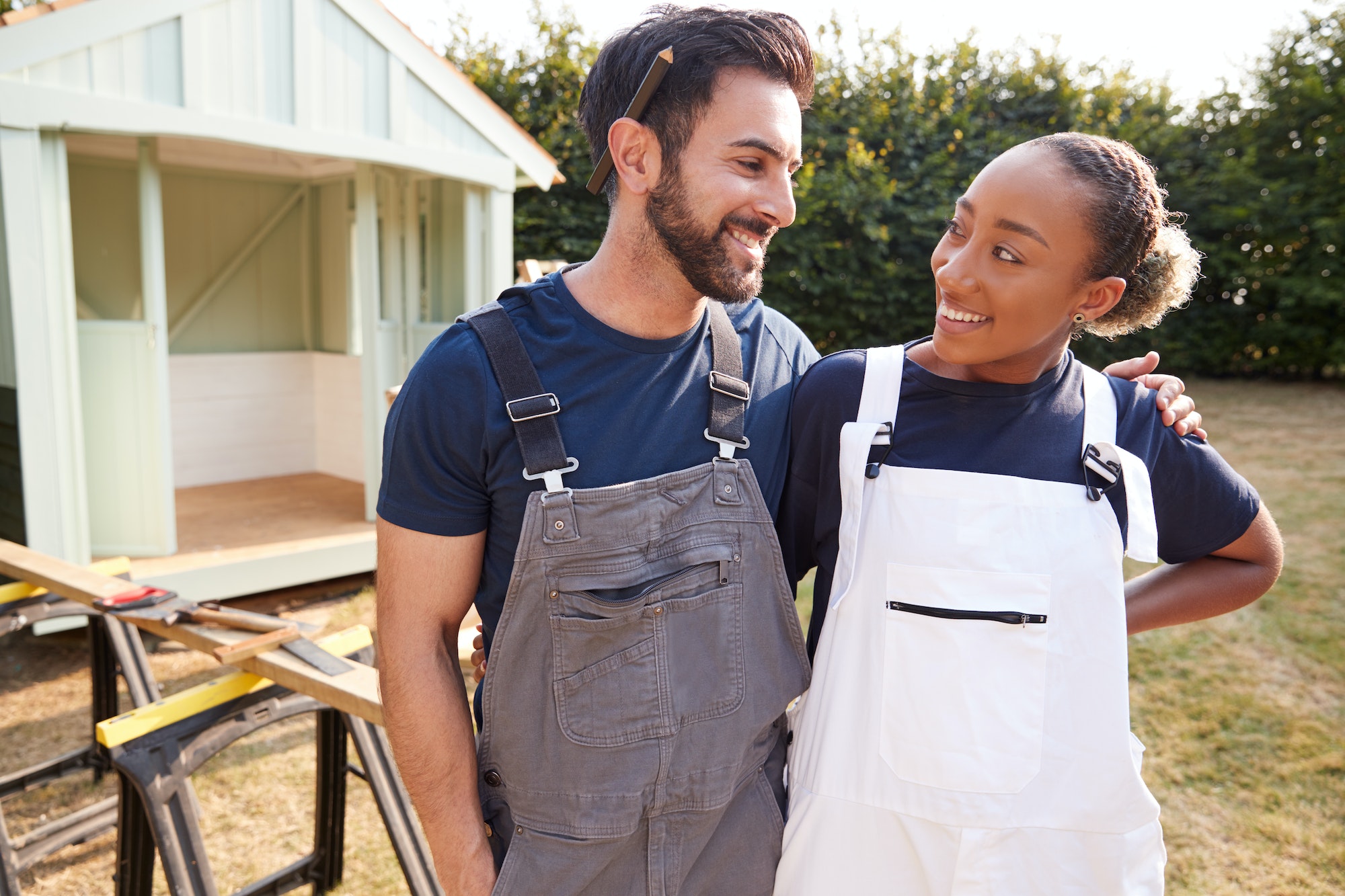 Couple Taking A Break From Building Outdoor Summerhouse In Garden