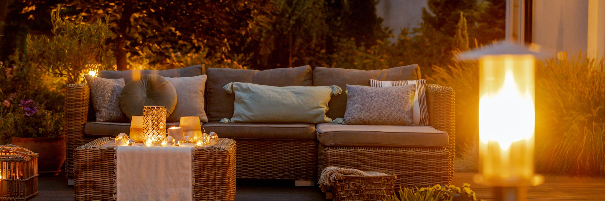 Warm summer night in the garden with trendy furniture, lights, lanterns and candles